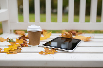 Image showing tablet pc and coffee cup on bench in autumn park