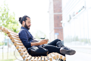 Image showing man with earphones and smartphone on city bench