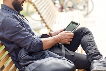 Image showing close up of man with tablet pc sitting on bench