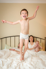 Image showing Mixed Race Chinese and Caucasian Boy Jumping In Bed with His Fam