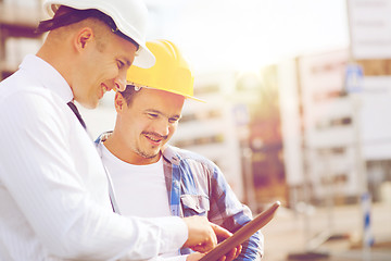 Image showing smiling builders in hardhats with tablet pc