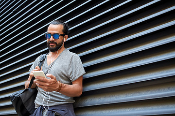 Image showing man with earphones and smartphone on city street