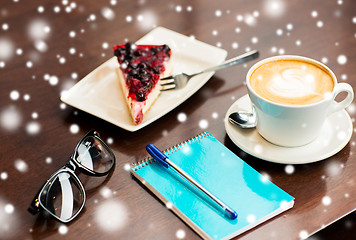 Image showing close up of notebook with pen, coffee cup and cake