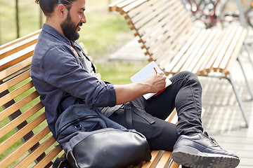 Image showing close up of man writing to notebook on city street