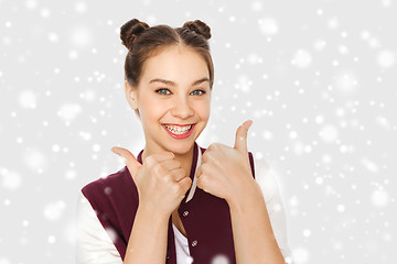 Image showing happy teenage girl showing thumbs up over snow