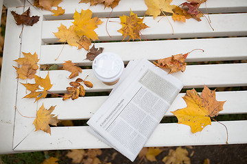 Image showing newspaper and coffee cup on bench in autumn park