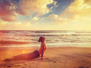 Image showing Woman practices yoga asana Urdhva Mukha Svanasana at the beach