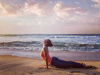 Image showing Woman practices yoga asana Urdhva Mukha Svanasana at the beach