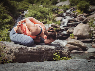 Image showing Young sporty fit woman doing yoga oudoors at tropical waterfall