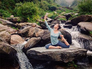 Image showing Sorty fit woman doing yoga asana outdoors at tropical waterfall