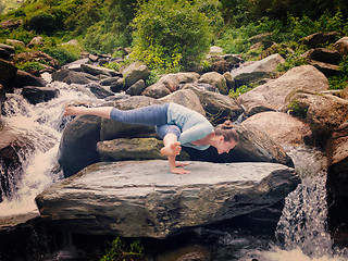 Image showing Young sporty fit woman doing yoga oudoors at tropical waterfall