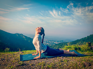 Image showing Woman practices yoga asana Urdhva Mukha Svanasana outdoors