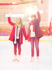 Image showing happy girls friends waving hands on skating rink