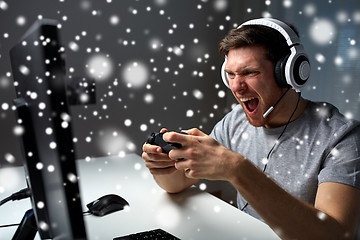 Image showing man in headset playing computer video game at home