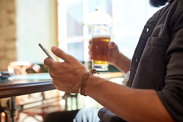 Image showing close up of man with smartphone and beer at pub