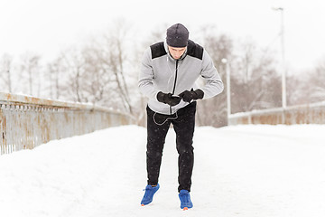 Image showing man with earphones and cellphone running in winter