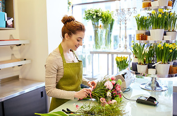 Image showing smiling florist woman making bunch at flower shop