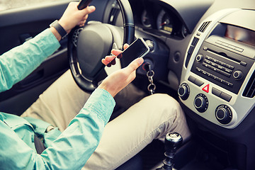 Image showing close up of man with smartphone driving car