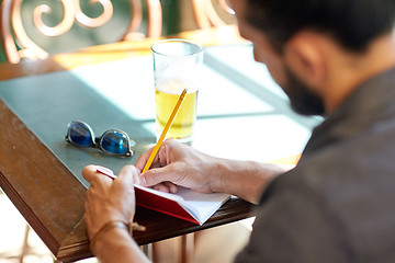 Image showing close up of man with beer and notebook at pub