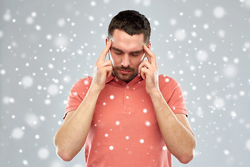 Image showing man suffering from head ache or thinking over snow