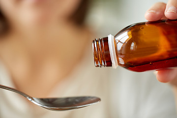 Image showing woman pouring medication from bottle to spoon