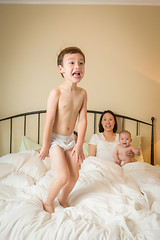 Image showing Mixed Race Chinese and Caucasian Boy Jumping In Bed with His Fam