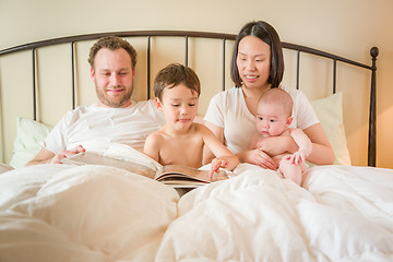 Image showing Chinese and Caucasian Baby Boys Reading a Book In Bed with Their