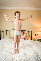 Image showing Mixed Race Chinese and Caucasian Boy Jumping In Bed with His Fam