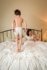 Image showing Mixed Race Chinese and Caucasian Boy Jumping In Bed with His Fam