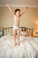 Image showing Mixed Race Chinese and Caucasian Boy Jumping In Bed with His Fam