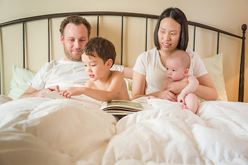 Image showing Chinese and Caucasian Baby Boys Reading a Book In Bed with Their