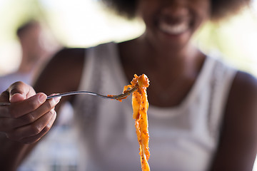 Image showing a young African American woman eating pasta