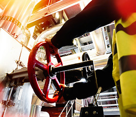 Image showing factory worker turning valve