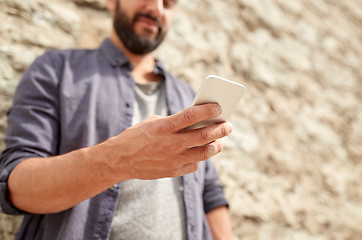 Image showing close up of man with smartphone at stone wall