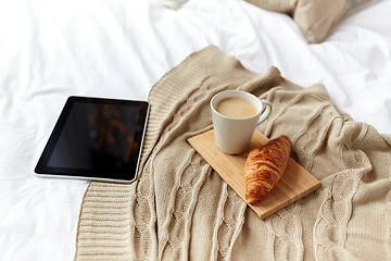 Image showing tablet pc, coffee and croissant on bed at home