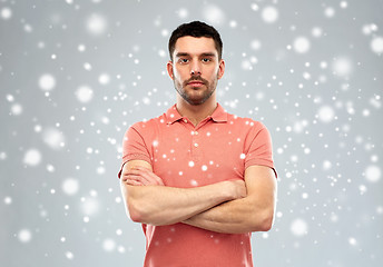 Image showing young man with crossed arms over snow background