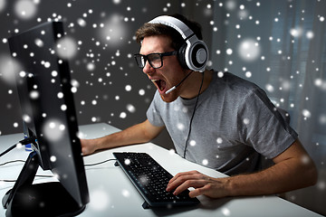 Image showing man in headset playing computer video game at home