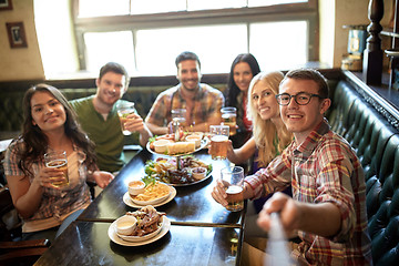 Image showing happy friends with selfie stick at bar or pub