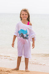 Image showing Cheerful girl basking on the beach wearing a large T-shirt parent