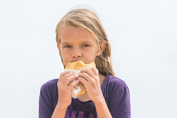 Image showing A hungry girl with an appetite chews delicious cake and looked into the frame