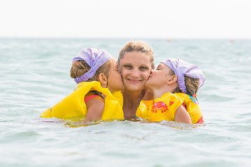 Image showing Daughters kiss mom swimming in the sea