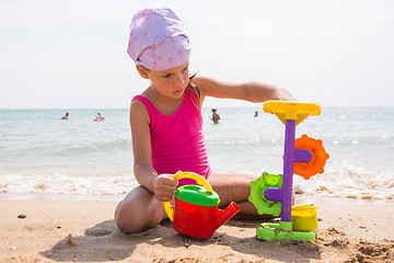 Image showing A child plays with toys in the sand on the beach