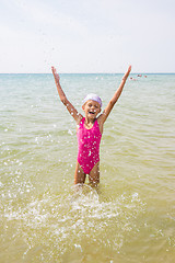 Image showing Happy girl let up splashes water standing in sea