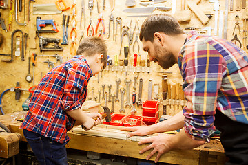 Image showing father and son with hammer working at workshop