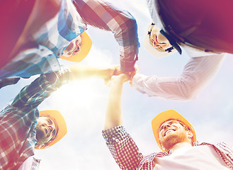 Image showing close up of builders in hardhats making high five