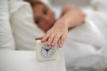 Image showing close up of woman with alarm clock in bed at home