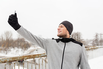 Image showing man taking selfie with smartphone in winter 