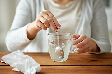 Image showing woman stirring medication in cup with spoon