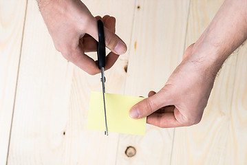 Image showing hand is cutting a sheet of yellow paper