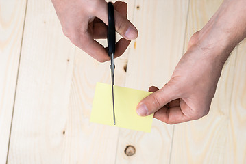 Image showing hand is cutting a sheet of yellow paper